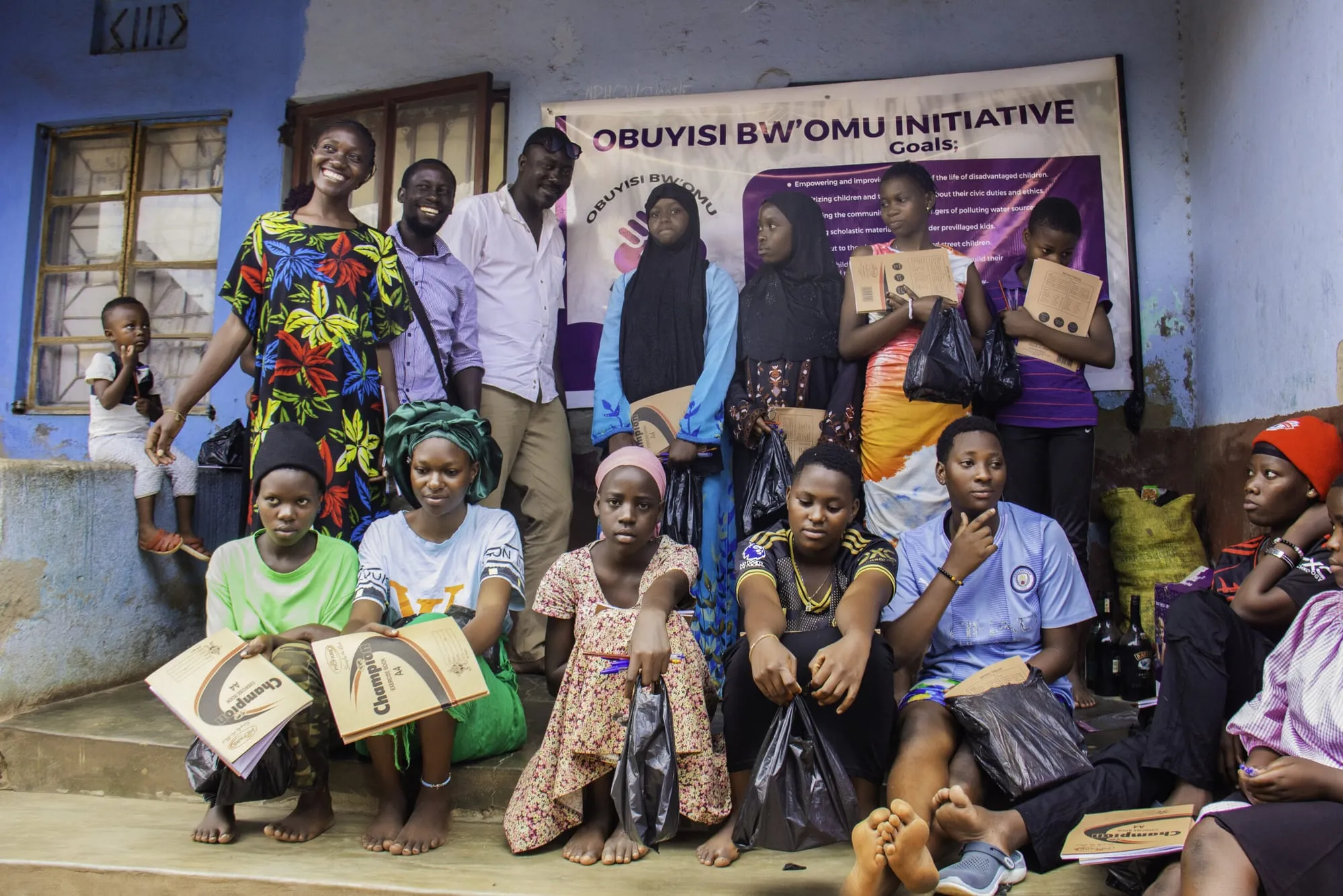 Girls seated with their new scholastic materials in front of the campaign banner